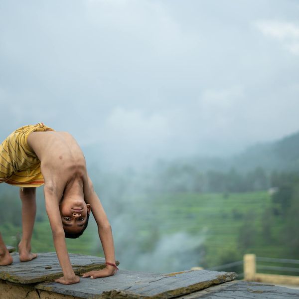 Person stretching energetically outdoors with a green natural background.
